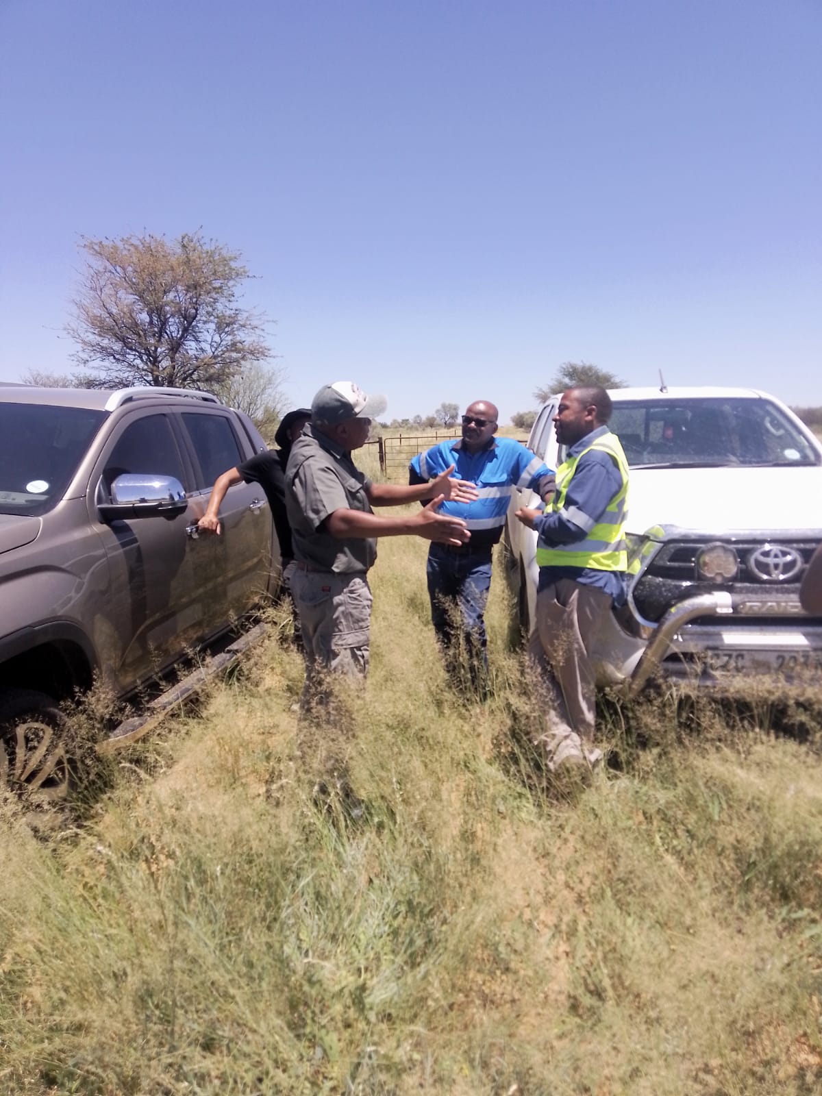 A group discussing a mining site beside two vehicles
