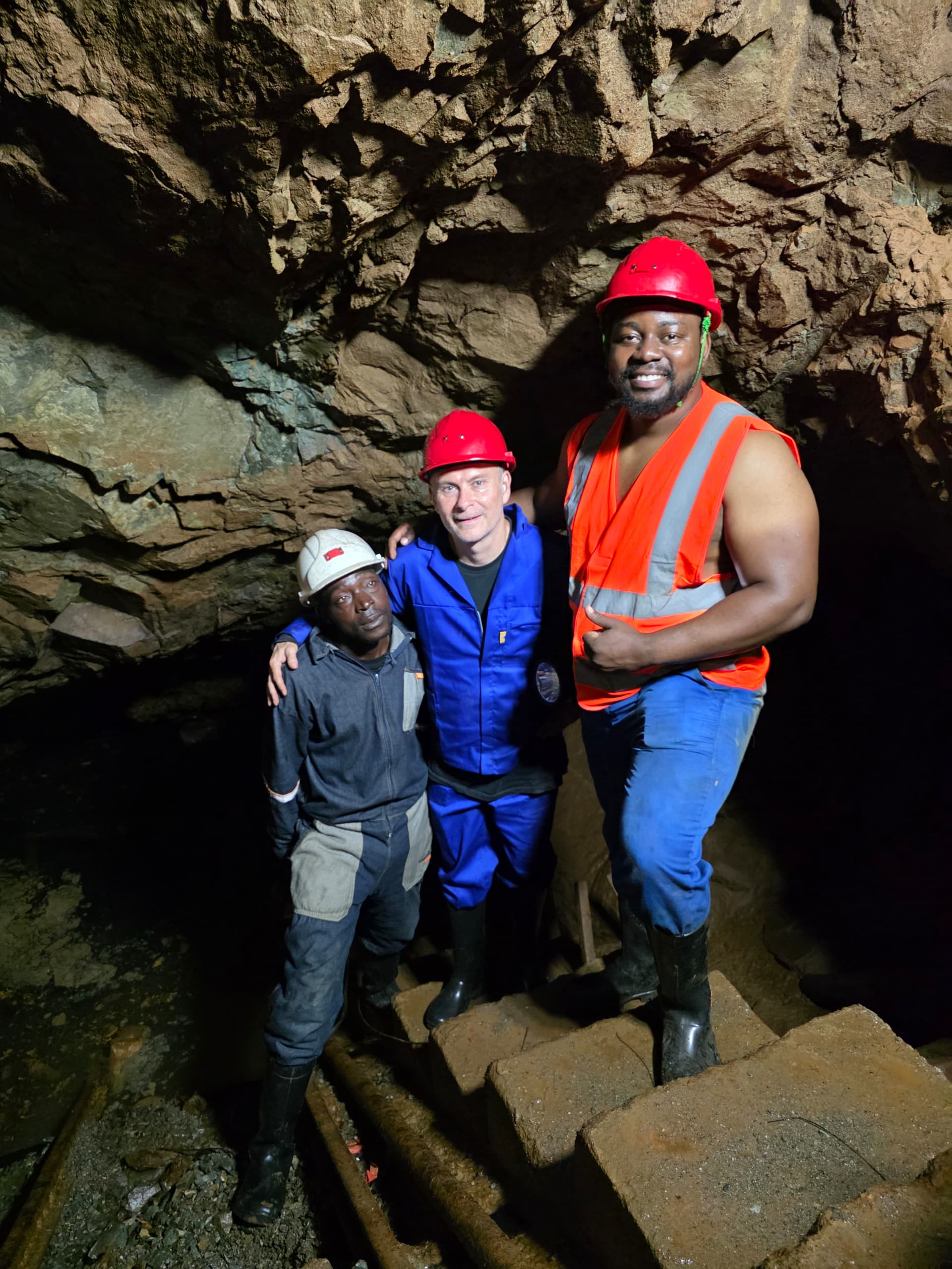 Three people wearing hard hats during an underground mine visit
